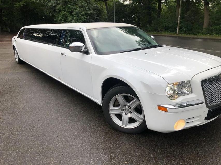 Weisse Chrysler 300C Stretchlimousine bei nasser Fahrbahn
