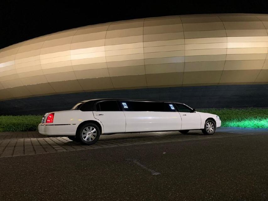 Weisse Lincoln Town Car Stretchlimousine bei Nacht vor beleuchtetem Gebaeude