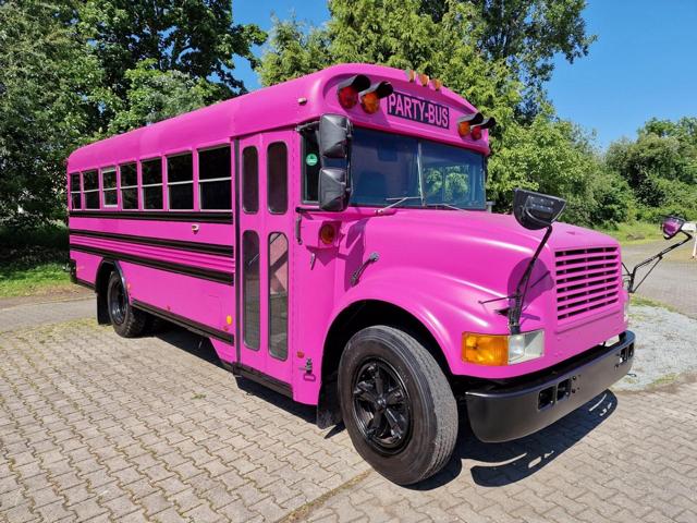 Pinker Partybus parkt vor grünen Bäumen